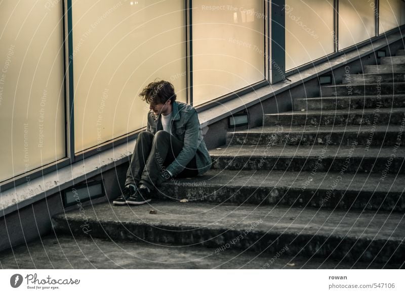 warten Mensch maskulin Junger Mann Jugendliche Erwachsene Stadt Fassade Fenster dunkel Treppe Glasfassade diagonal kalt sitzen Einsamkeit Sorge Traurigkeit