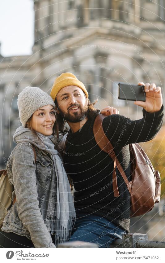 Junges Paar macht ein Selfie mit dem Berliner Dom im Hintergrund, Berlin, Deutschland Touristen Rucksäcke Telekommunikation telefonieren Handies Handys