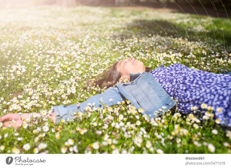 Entspannte junge Frau liegend auf Blumenwiese in einem Park Parkanlagen Parks Blumenwiesen weiblich Frauen liegt entspannt entspanntheit relaxt Wiese Wiesen