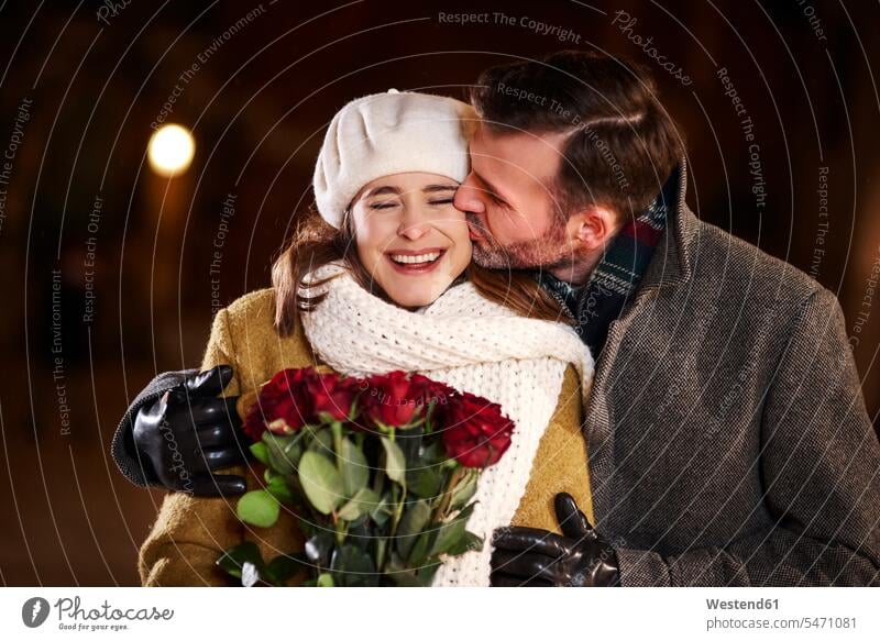 Mann küsst seine lachende Freundin im Winter Männer männlich winterlich Winterzeit küssen Küsse Kuss positiv Emotion Gefühl Empfindung Emotionen Gefühle fühlen