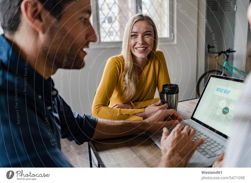 Geschäftsfrau lächelnd auf Geschäftsmann während eines Treffens im Büro Business Geschäftsleben Geschäftswelt geschäftlich Team Office Büros Laptop Notebook