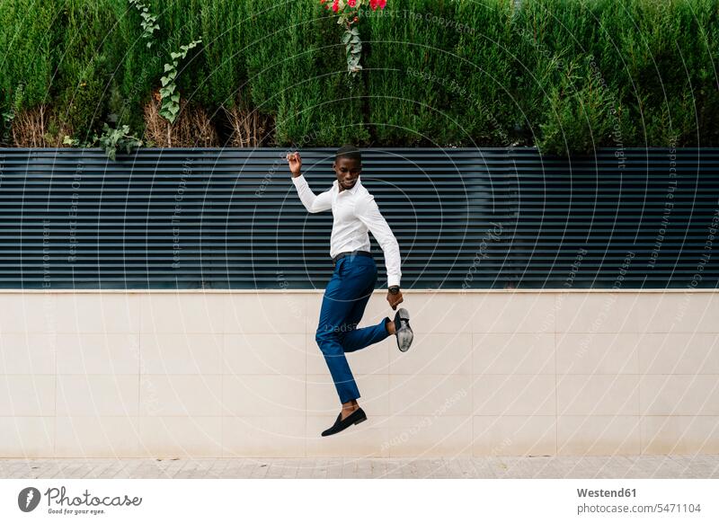 Männlicher Profi springt auf Bürgersteig gegen Stadtmauer Farbaufnahme Farbe Farbfoto Farbphoto Spanien Außenaufnahme außen draußen im Freien Tag