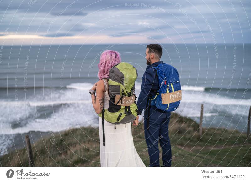 Das Brautpaar auf dem Aussichtspunkt und das Meer im Hintergrund Rucksäcke abends freuen Glück glücklich sein glücklichsein gefühlvoll Emotionen Empfindung
