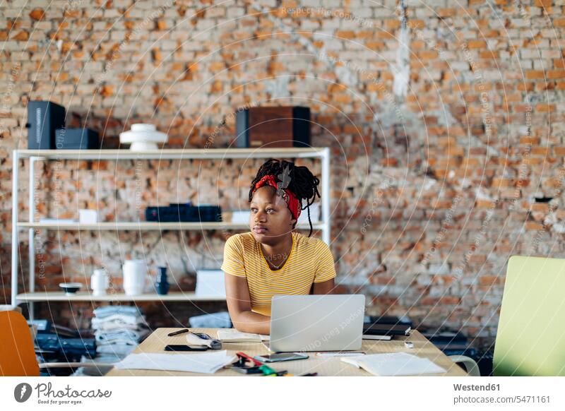Junge Frau sitzt mit Laptop am Tisch Leute Menschen People Person Personen Afrikanisch Afrikanische Abstammung dunkelhäutig Farbige Farbiger Schwarze 1 Ein