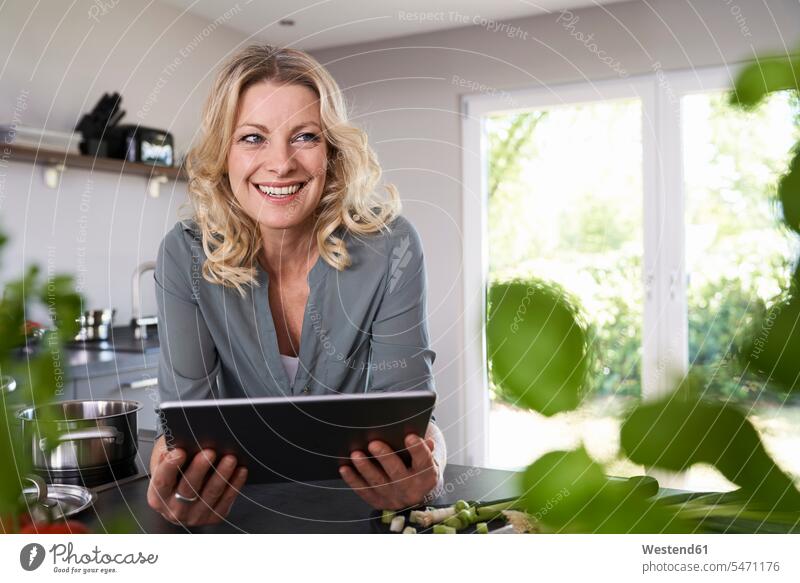 Lächelnde Frau benutzt Tablette in der Küche weiblich Frauen Küchen Tablet Computer Tablet-PC Tablet PC iPad Tablet-Computer lächeln Erwachsener erwachsen