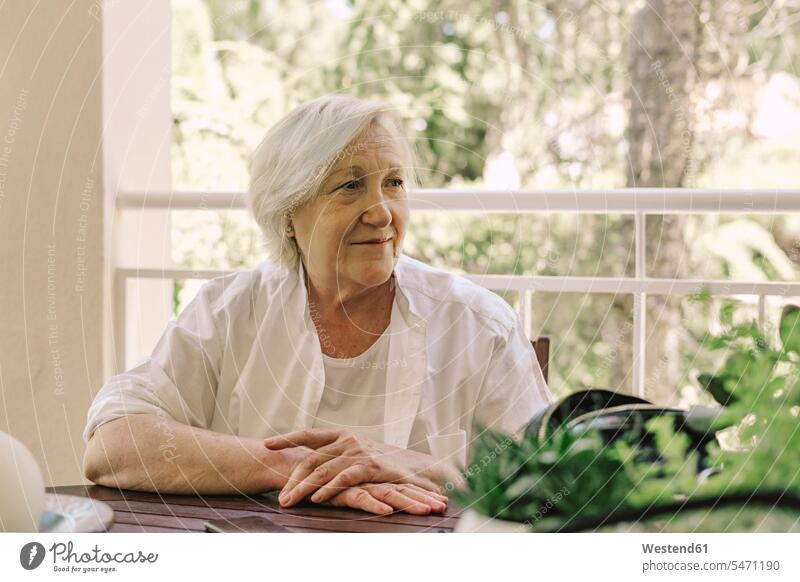 Nachdenkliche ältere Frau schaut weg, während sie am Tisch auf dem Balkon sitzt Farbaufnahme Farbe Farbfoto Farbphoto Spanien Freizeitbeschäftigung Muße Zeit