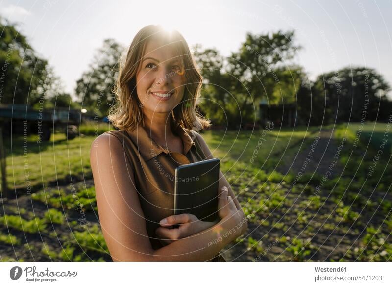 Lächelnde junge Frau mit Tablette in der Hand auf einem Bauernhof auf dem Land geschäftlich Geschäftsleben Geschäftswelt Geschäftsperson Geschäftspersonen