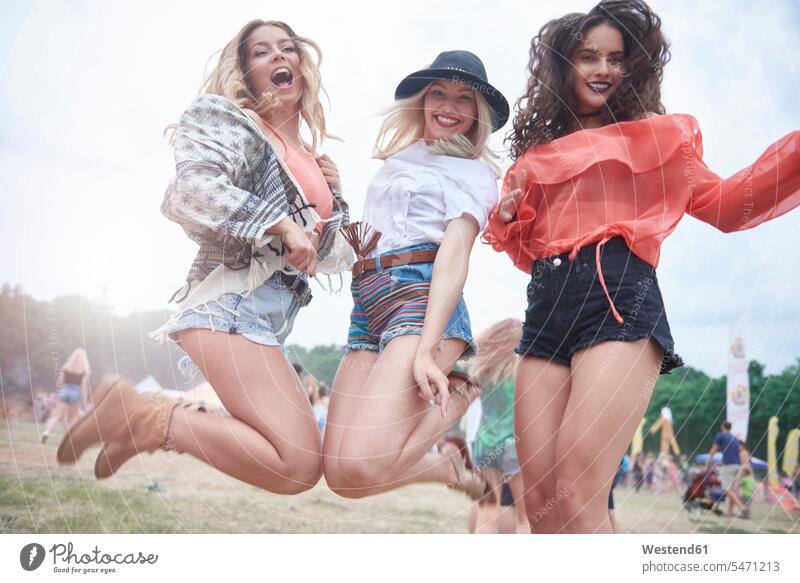 Glückliche Freunde springen während des Musikfestivals Freundinnen ausgelassen Ausgelassenheit Luftsprung Luftsprünge einen Luftsprung machen Luftspruenge