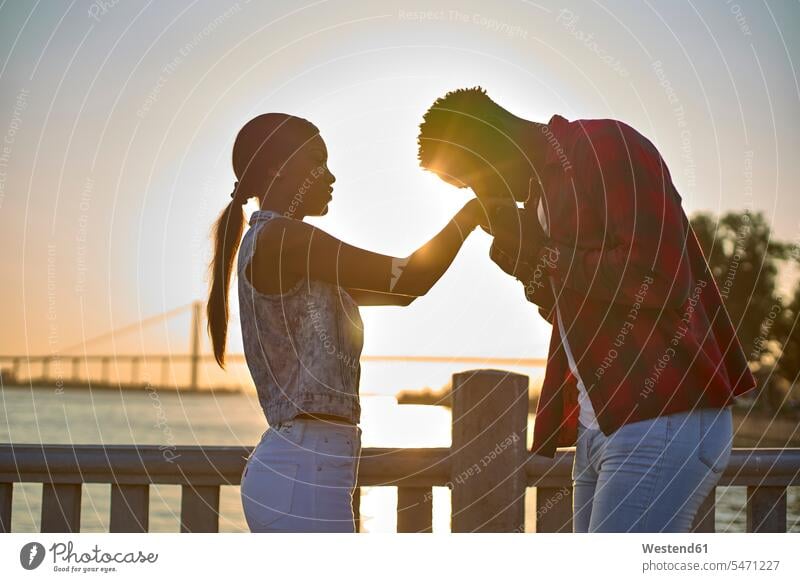 Junges Paar hält bei Sonnenuntergang Händchen Leute Menschen People Person Personen Afrikanisch Afrikanische Abstammung dunkelhäutig Farbige Farbiger Schwarze 2