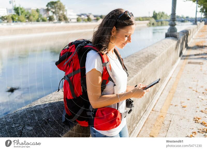 Junge Rucksacktouristin mit Smartphone an einem Fluss in Verona, Italien Leute Menschen People Person Personen Europäisch Kaukasier kaukasisch 1 Ein ein Mensch