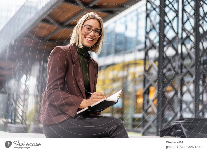 Porträt einer glücklichen jungen Geschäftsfrau mit Notizbuch in der Stadt geschäftlich Geschäftsleben Geschäftswelt Geschäftsperson Geschäftspersonen