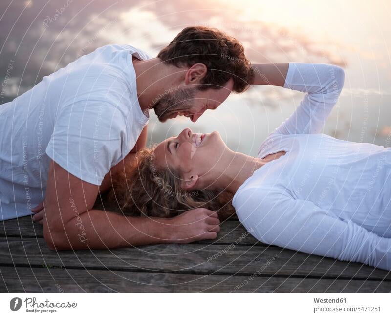 Romantisches Paar liegt auf dem Steg und küsst sich Kuss Küsse Jahreszeiten Frühjahr Lenz Glück glücklich sein glücklichsein gefühlvoll Emotionen Empfindung