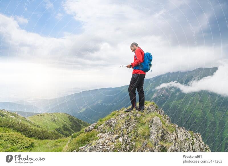 Mann steht auf einem Hügel und überprüft seine Karte in den Karpaten, Rumänien wandern wandernd wandert stehen stehend Wanderer bergsteigen Bergsteiger