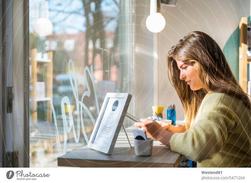 Junge Frau benutzt Tablette in einem Café Tablet Computer Tablet-PC Tablet PC iPad Tablet-Computer weiblich Frauen Cafe Kaffeehaus Bistro Cafes Cafés