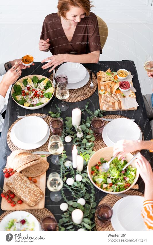Freunde sitzen am gedeckten Tisch, genießen ihre Dinnerparty, Blick von oben feiern Gastlichkeit Gastfreundschaft Freundschaft Kameradschaft Salat Salate lustig