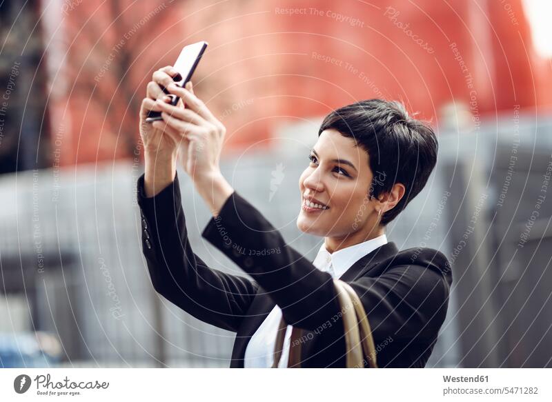 Porträt einer lächelnden jungen Geschäftsfrau, die ein Selfie mit ihrem Mobiltelefon macht Selfies Portrait Porträts Portraits Smartphone iPhone Smartphones