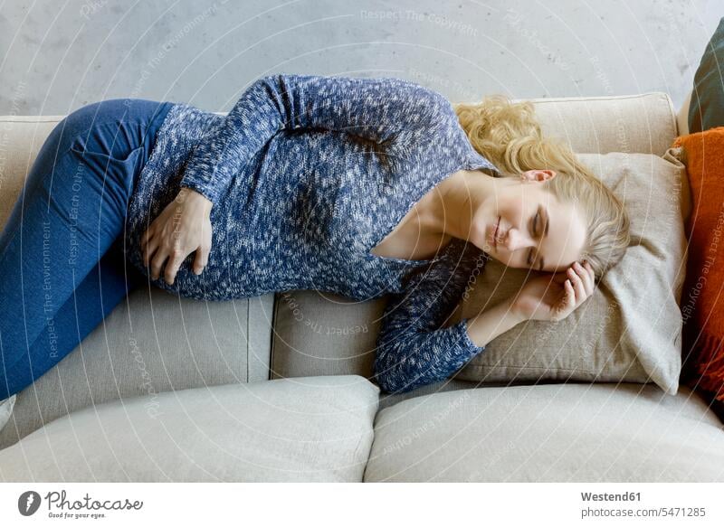 Schwangere Frau schläft zu Hause auf dem Sofa schwanger schwangere Frau schlafen schlafend weiblich Frauen Portrait Porträts Portraits liegen liegend liegt