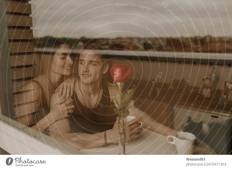 Romantisches junges Paar mit roter Rose hinter Fensterscheibe Fensterscheiben geniessen Genuss Glück glücklich sein glücklichsein gefühlvoll Emotionen