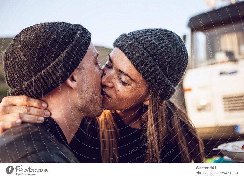 Küssendes Paar mit wolligen Hüten Pärchen Paare Partnerschaft Wollmütze Wollmützen Strickmütze Strickmützen küssen Kuss Mensch Menschen Leute People Personen
