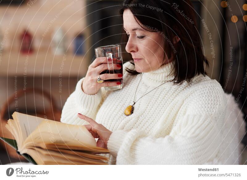 Reife Frau mit einem heißen Getränk beim Lesen eines Buches weiblich Frauen lesen Lektüre Heißgetränk heißes Getränk entspannt entspanntheit relaxt Bücher