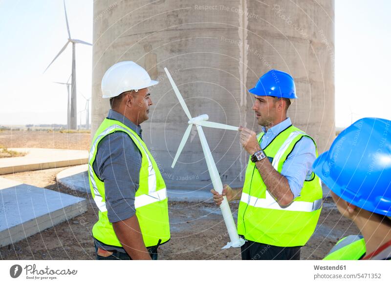 Drei Ingenieure mit Windturbinenmodell diskutieren über einen Windpark Modell Modelle besprechen Besprechung Windrad Windräder Windenergieanlage WEA WEAs