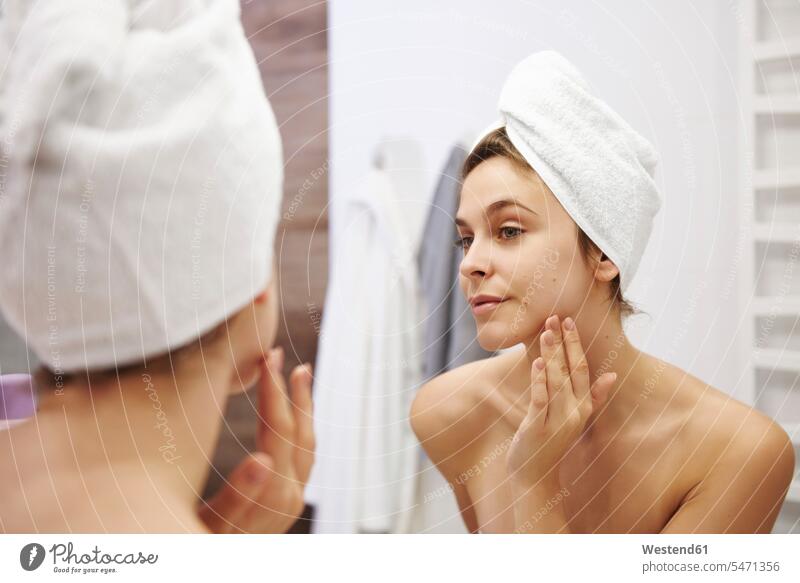 Spiegelbild einer jungen Frau, die ihr Gesicht im Badezimmer untersucht Spiegelbilder mustern musternd untersuchen prüfen begutachten weiblich Frauen schauen