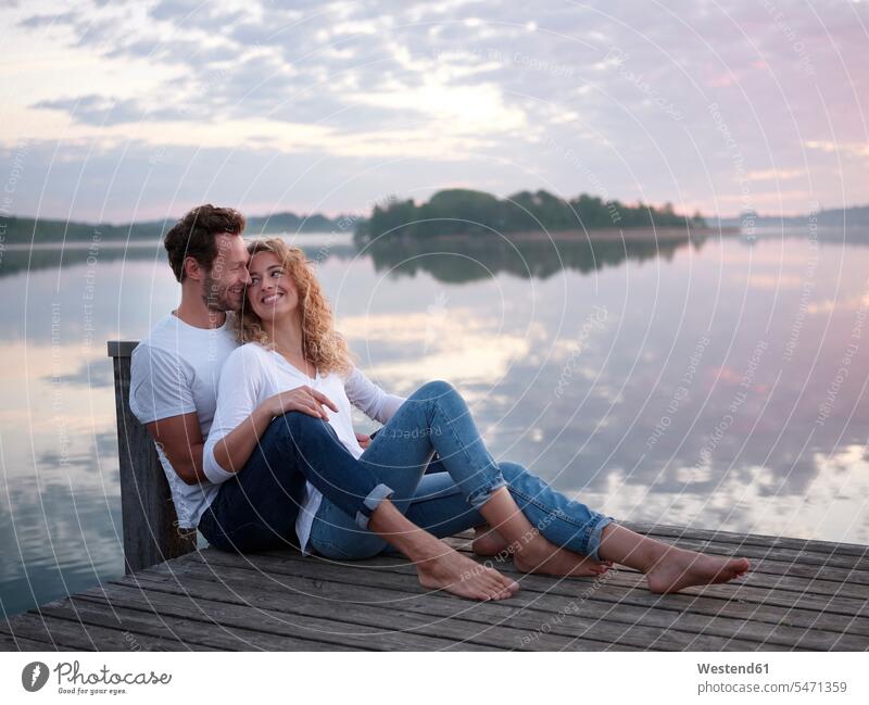 Romantisches Paar sitzt auf einem Steg am See sitzend früh Frühe Morgen Jahreszeiten Frühjahr Lenz freuen behüten behütet geborgen Sicherheit Glück