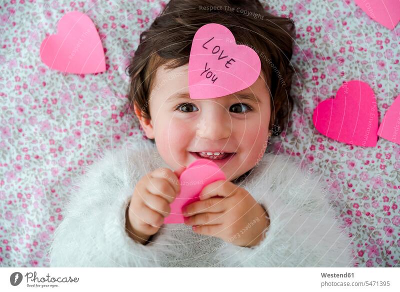 Porträt eines kleinen Mädchens mit rosa herzförmigen Post-it-Aufklebern weibliche Babys weibliches Baby weibliche Babies Herz Herzform Herzformen Herzen
