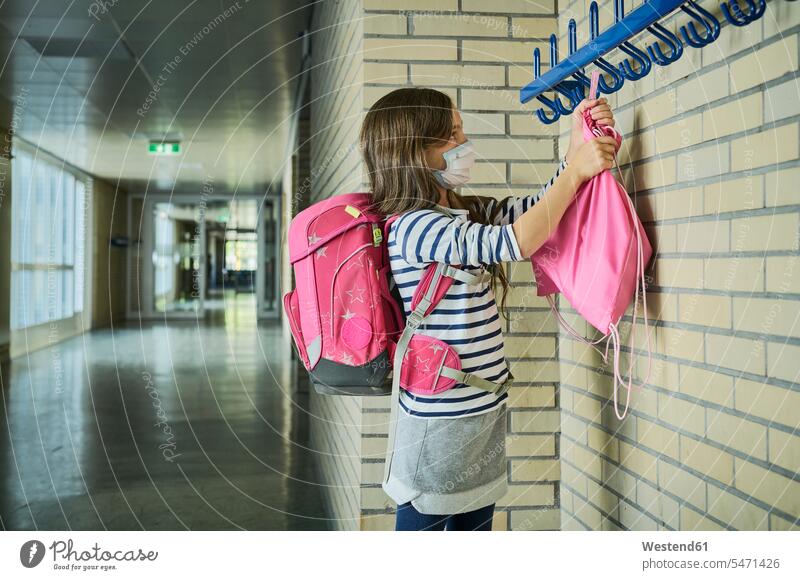 Mädchen trägt Maske in der Schule Aufhängebeutel Schüler rosa stehen Gesundheit Schutz Sicherheit Flur Innenaufnahme Tag Schülerin Freizeitkleidung lange Haare