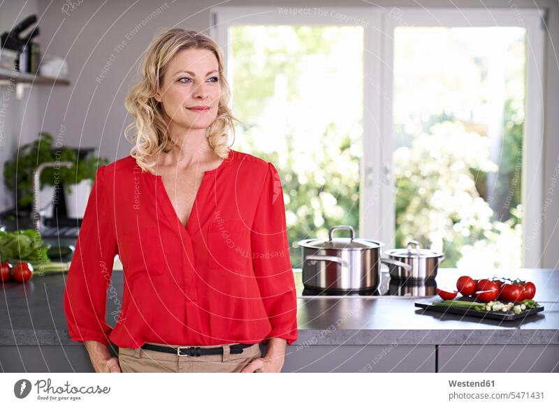 Selbstbewusste Frau in roter Bluse steht in Küche rotes Blusen stehen stehend Zuversicht Zuversichtlich Selbstvertrauen selbstbewusst Vertrauen Küchen weiblich