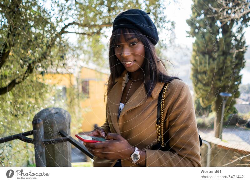 Porträt einer lächelnden Touristin im Freien Touristen Taschen Handtaschen Telekommunikation telefonieren Handies Handys Mobiltelefon Mobiltelefone entspannen
