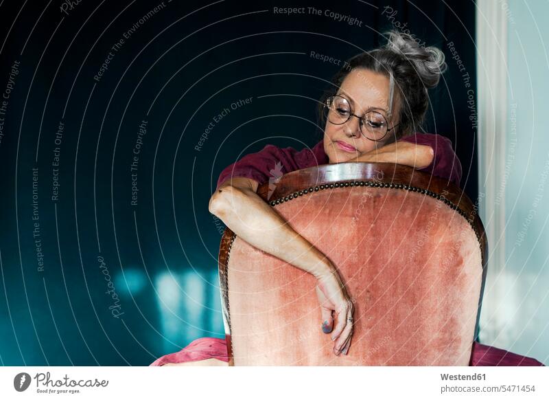 Traurige, nachdenkliche ältere Frau sitzt zu Hause auf einem Stuhl Farbaufnahme Farbe Farbfoto Farbphoto Spanien Freizeitkleidung Freizeitbekleidung casual