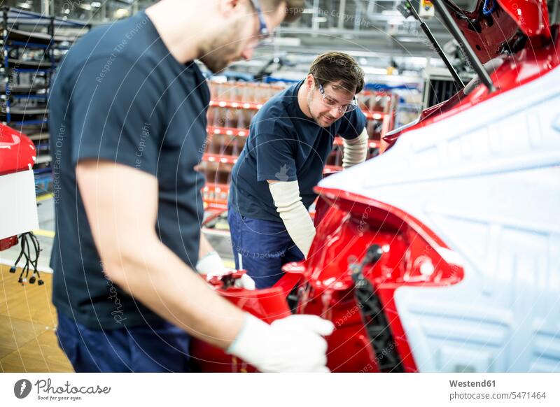 Zwei Kollegen arbeiten in einer modernen Autofabrik Arbeitskollege Arbeitskollegen Job Berufe Berufstätigkeit Beschäftigung Jobs Arbeiter T-Shirts KFZ
