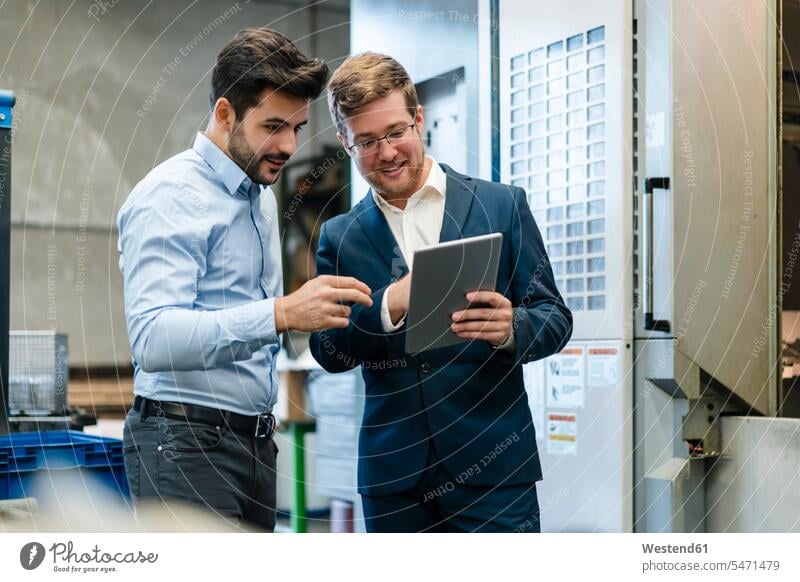 Lächelnde Geschäftsleute mit digitalem Tablet in der Industrie Farbaufnahme Farbe Farbfoto Farbphoto Innenaufnahme Innenaufnahmen innen drinnen Österreich