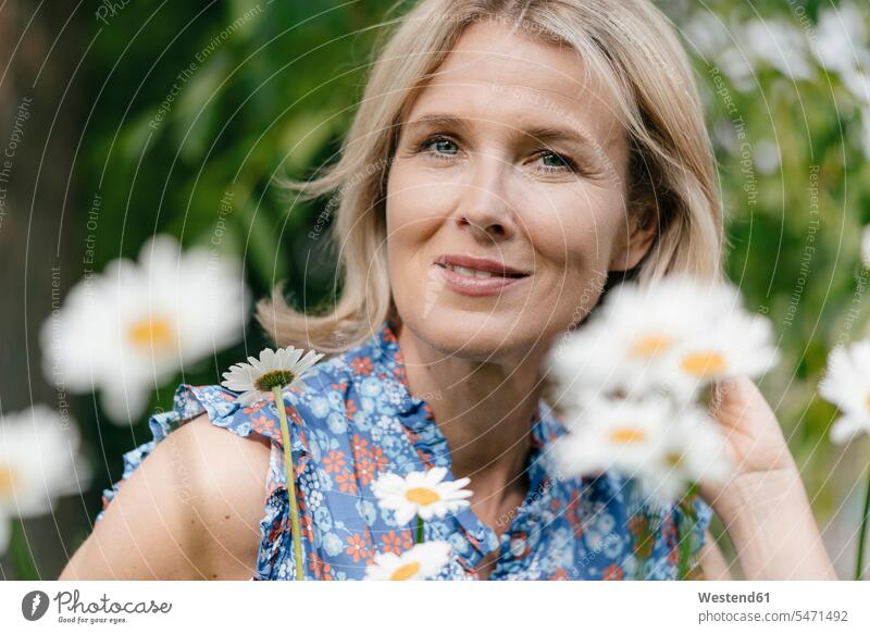 Bildnis einer lächelnden reifen Frau mit Blumen Blüte weiblich Frauen Portrait Porträts Portraits Pflanze Pflanzenwelt Flora Erwachsener erwachsen Mensch