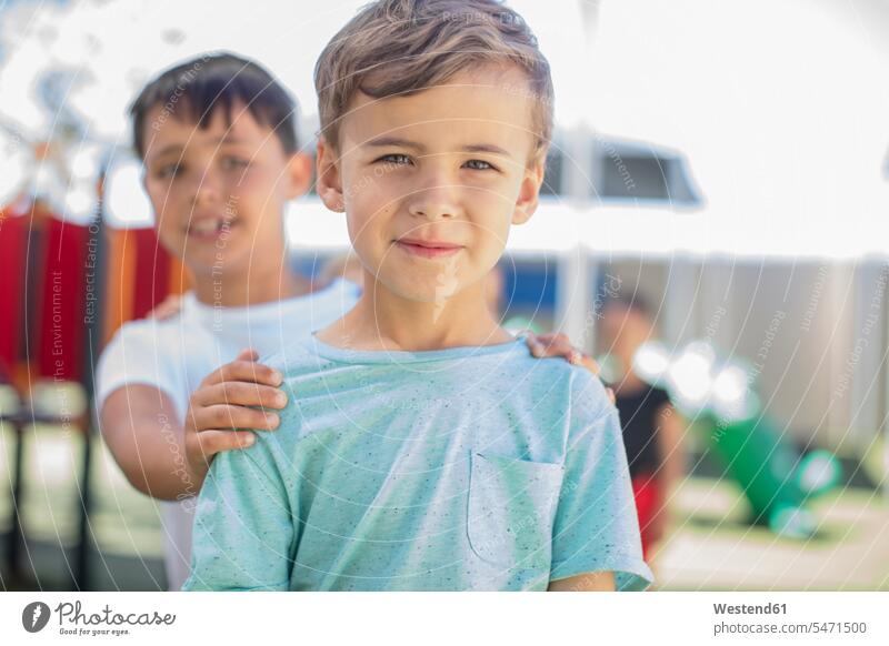 Porträt eines lächelnden Jungen mit Freunden auf einem Spielplatz im Kindergarten Spielplätze Spielfeld Spielplaetze Buben Knabe Knaben männlich Portrait