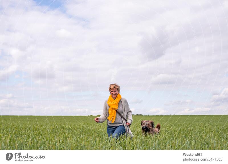 Glückliche Frau geht mit Hund auf einem Feld spazieren Leute Menschen People Person Personen Alleinstehende Alleinstehender Singles Unverheiratete