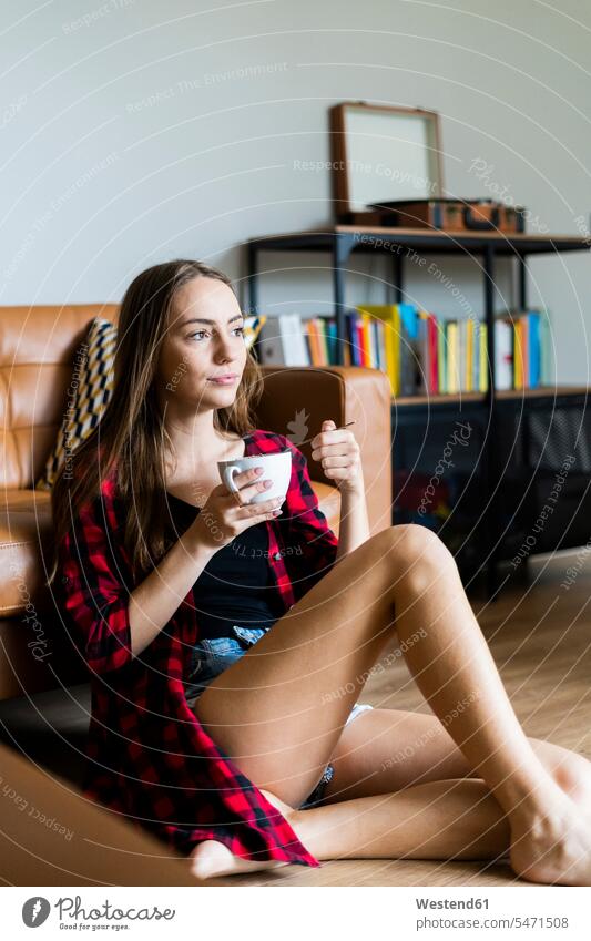Entspannte junge Frau isst zu Hause im Wohnzimmer Müsli Leute Menschen People Person Personen Alleinstehende Alleinstehender Singles Unverheiratete
