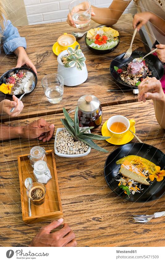 Menschen, die sich um einen Holztisch versammeln und verschiedene Speisen essen und trinken Versammlung Holztische essend Gruppe Gruppe von Menschen