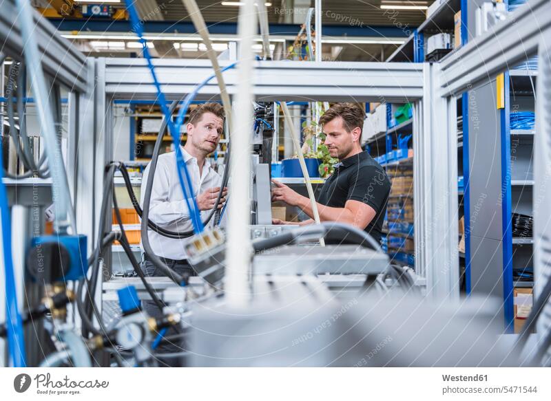 Zwei Männer haben eine Besprechung an einer Maschine in der Fabrik Arbeitskollege Arbeitskollegen Kollege Job Berufe Berufstätigkeit Beschäftigung Jobs