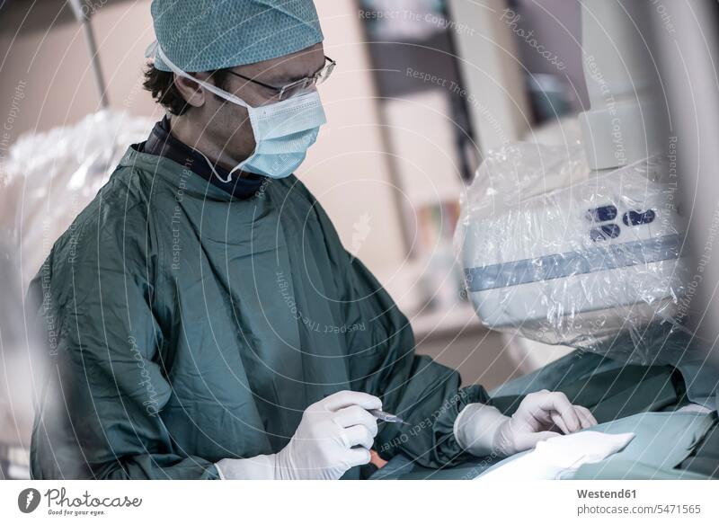Neuroradiologe im OP-Kittel hält Skalpell Arzt Doktoren Ärzte Operationskittel halten Operationen operieren Chirurgie Krankenhaus Kliniken Krankenhäuser