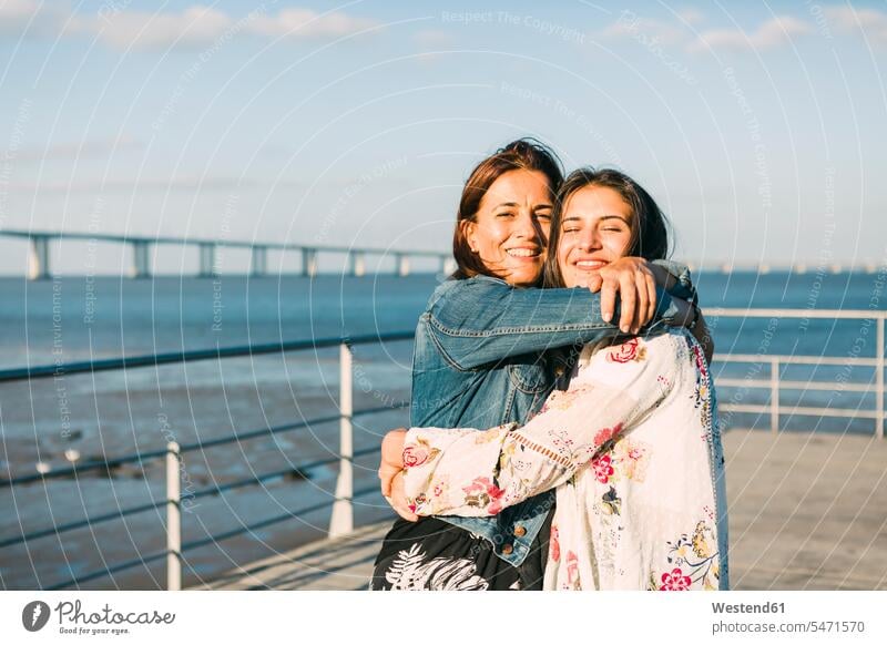 Glückliche Mutter umarmt Tochter, während sie am Meer steht Farbaufnahme Farbe Farbfoto Farbphoto Portugal Freizeitbeschäftigung Muße Zeit Zeit haben