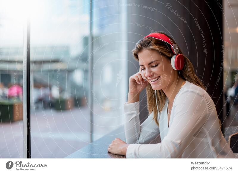 Glückliche junge Frau, die mit Kopfhörern Musik hört glücklich glücklich sein glücklichsein weiblich Frauen hören hoeren Kopfhoerer Erwachsener erwachsen Mensch