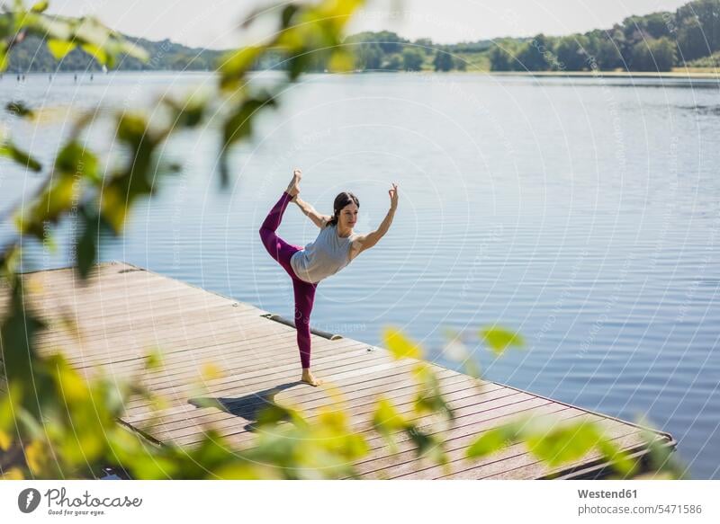 Reife Frau übt Yoga im Sommer auf einem Steg an einem See Seen Sommerzeit sommerlich Stege Anlegestelle üben ausüben Übung trainieren reife Frau reife Frauen
