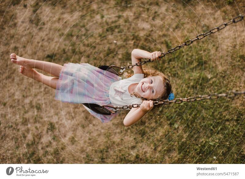 Glückliches kleines Mädchen auf einer Schaukel Roecke Röcke Schaukeln entspannen relaxen Jahreszeiten sommerlich Sommerzeit freuen Frohsinn Fröhlichkeit