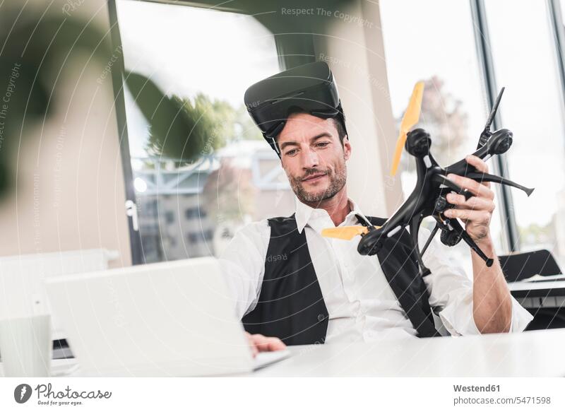 Geschäftsmann sitzt im Büro und arbeitet an einer Drohne, mit VR-Brille Entwicklung entwickeln Entwicklungen Laptop benutzen Laptop benützen