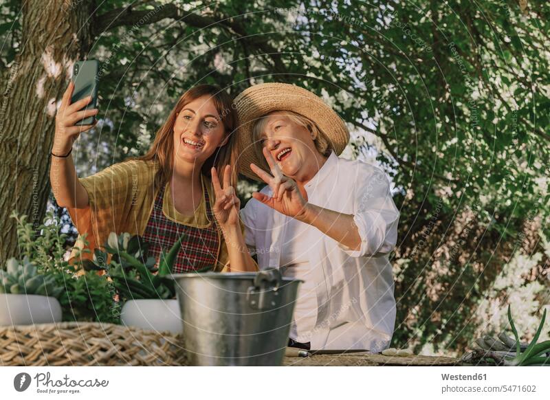 Mittelgroße erwachsene Frau beim Selbermachen mit fröhlicher Mutter im Hof Farbaufnahme Farbe Farbfoto Farbphoto Spanien Freizeitbeschäftigung Muße Zeit