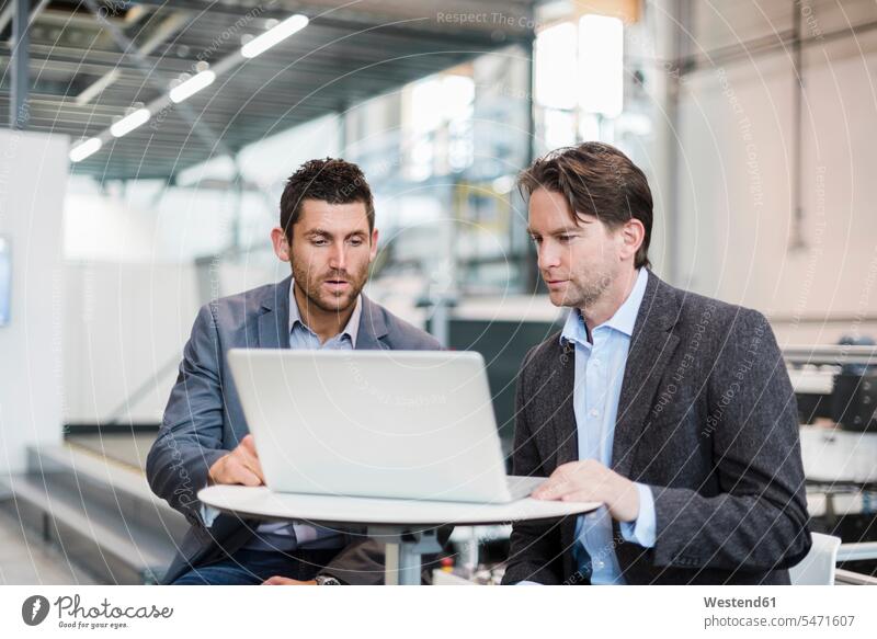 Zwei Geschäftsleute teilen sich einen Laptop in der Fabrik Notebook Laptops Notebooks Geschäftsmann Businessmann Businessmänner Geschäftsmänner modern Fabriken