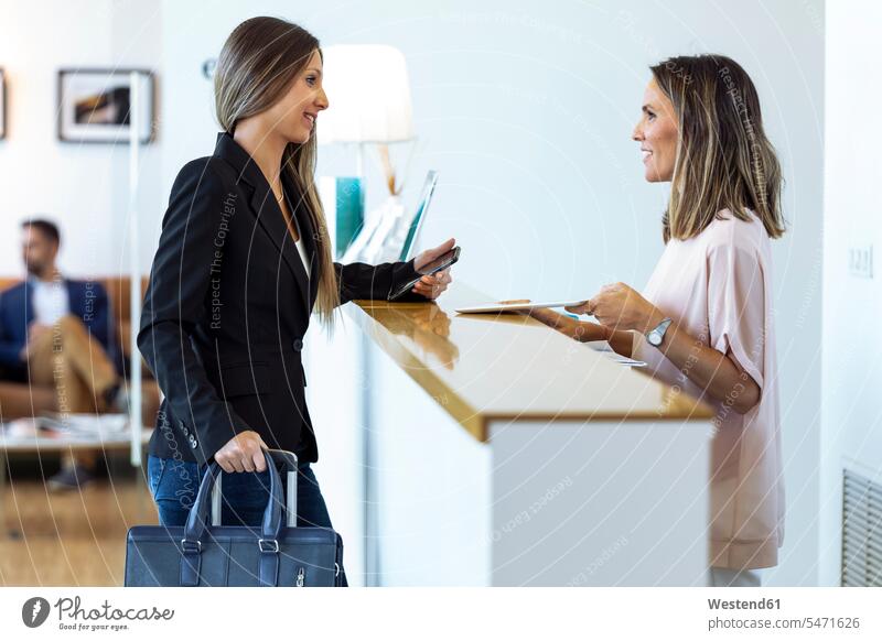 Lächelnde Geschäftsfrauen im Gespräch mit Frau am Empfang Job Berufe Berufstätigkeit Beschäftigung Jobs geschäftlich Geschäftsleben Geschäftswelt