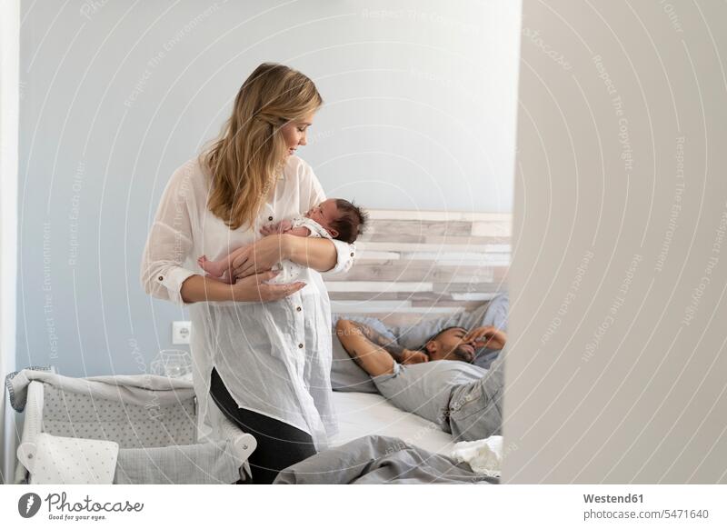 Mutter hält ihr neugeborenes Baby im Schlafzimmer mit Vater schlafen im Hintergrund Familie mit einem Kind Fokus Auf Den Vordergrund Fokus Auf Dem Vordergrund